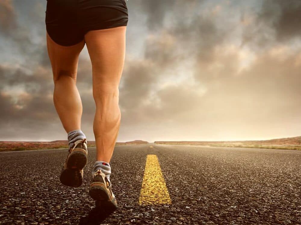 A runner on an open road at sunrise.